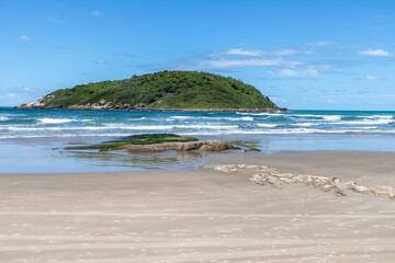 Beach view with sand, rocks, waves and island in background