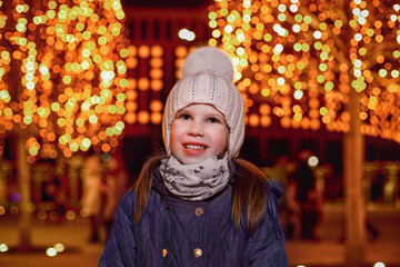 Girl in warm clothes against the background of New Year's lights