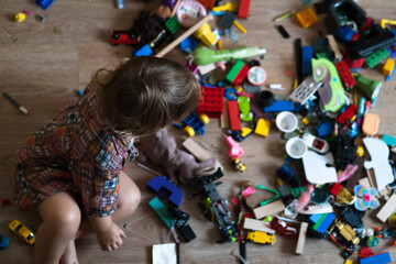 Mess in the nursery.Baby plays while sitting on the floor in colorful blocks. Homeschooling concept 