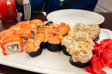 Japanese sushi and rolls and ginger are laid out on a white plate in the restaurant. Set of sushi rolls. Japanese cuisine.