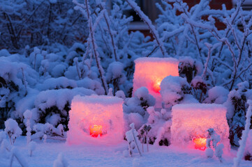 Ice lanterns and bush branches covered with fresh snow, twilight in the in the winter garden.