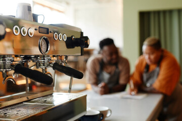 Selective focus on coffee machine shot young man and woman starting workday in small cafe with creating menu
