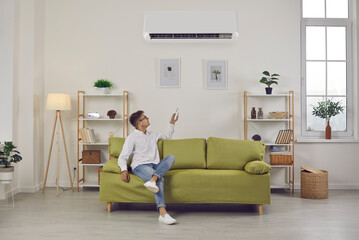 Man switching air conditioning modes sets comfortable temperature while enjoying fresh air at home....
