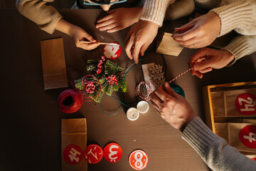 Close-up top view of unrecognizable family making Christmas advent calendar together sitting at...