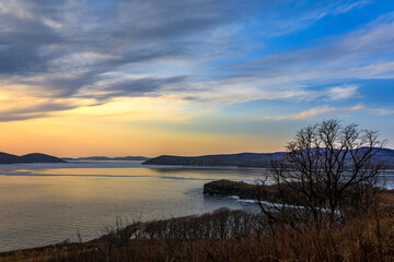 A picturesque sunset on the Russky Island in Vladivostok. The sun sets against the background of the autumn hills of an island in the Sea of Japan.