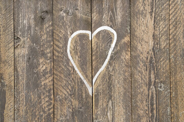Old wooden board background with white heart shape painted on. Love sign concept