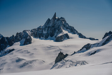 View of glaciers on Mont Blanc Massif and famous peak Dent du Geant, Chamonix, France. High alpine snow covered mountain landscape with creavasses, snow, rock wall and ridge. Alpinism, mountaineering.