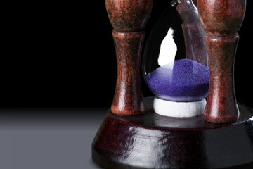 An hourglass with little time left sand on the desk.