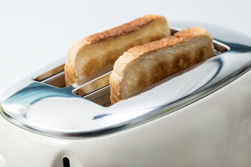 Slices of bread are prepared for breakfast. The toaster has two crispy toasts.