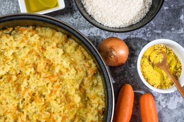 Italian vegan Risotto in a large pan with ingredients - rice, onion, carrots, spices, olive oil