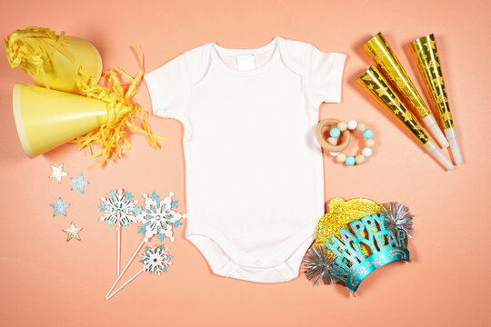 Baby romper onesie bodysuit product mockup. New Year theme SVG craft product mockup styled with party hats and blowers decorations. Gold and blue theme creative composition flatlay.