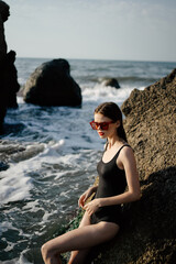 woman in swimsuit sunglasses ocean rocks posing
