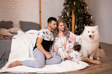 Young couple sitting at home in Christmas time with samoyed dog