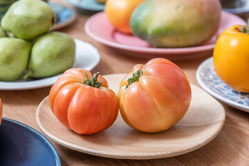 Delicious dishes with super tasty antique pink tomatoes on wooden textured plate surrounded by other fruits and vegetables