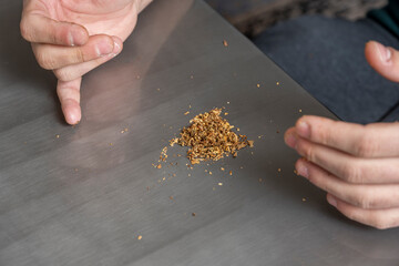 Hands preparing blond tobacco mix for smoking with rolling paper