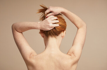 Minimal back view of young red haired woman with nude shoulders, copy space