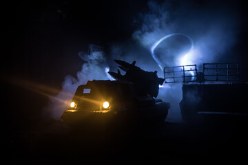 Creative artwork decoration. Silhouette of mobile air defence truck with radar antenna during sunset. Satellite dishes or radio antennas against evening sky.