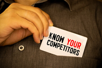 Businessman putting a card with text know your competitors in the pocket