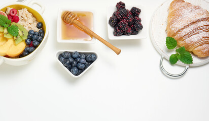 plate with oatmeal and fruit, half a ripe orange and freshly squeezed juice in a transparent glass decanter, honey in a bowl on a white table. Healthy breakfast