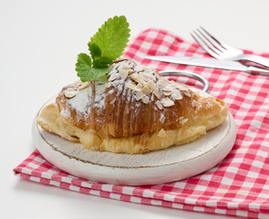 Baked croissant sprinkled with sugar on wooden board, red napkin