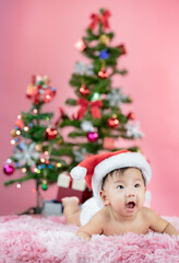 Happy cute baby wearing Santa hat with Christmas pink background