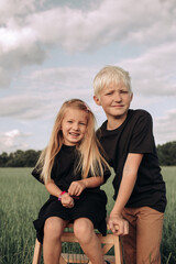 Portrait of blonde little girl with her elder brother, concept of happy childhood, kid's friendship. Two white haired kids looking at camera