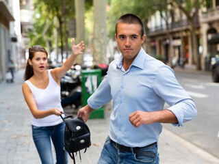 Male thief stealing woman bag on street of city