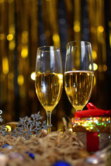 Two glasses of champagne on golden background with christmas gifts