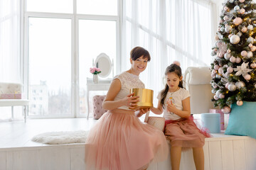 Naklejka premium Family values. Love and friendship of mother and daughter. Mom gives a Christmas present to her daughter.