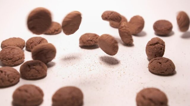 Kruitnoten (Dutch candy) falling and bouncing around. Close up. White background.