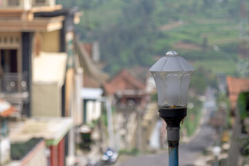 The street lamp is made of glass, with the background of the Mount Merapi hiking trail