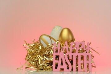 Easter holiday background.Happy easter. inscription Happy Easter and Golden Easter eggs in a nest of golden tinsel on a pink background.holiday background. Spring religious holiday