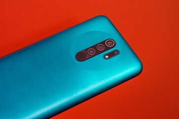 the back cover of a smartphone in blue with a camera on an orange background.