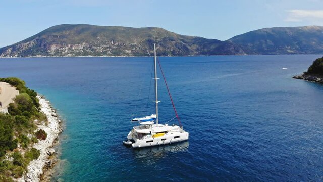 Boats Floating On Calm Blue Sea In Foki Beach, Kefalonia, Greece. aerial pullback