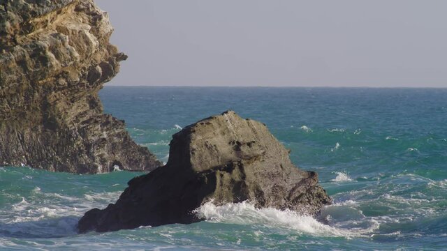 Ocean Waves Crashing Against Rock And Rugged Cliff At The Beach. - wide shot