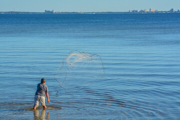 A Fisherman throwing His cast net to get bait fish. On Hammock Bay in Freeport, Walton County, Florida - obrazy, fototapety, plakaty