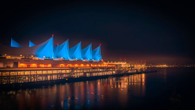 Canada Place and North Vancouver at night with lights reflected in the water in Downtown Vancouver, British Columbia, Canada.
