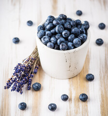 Blueberries in white ceramic bowl on rustic wooden background. Selective focus. Shallow depth of field.