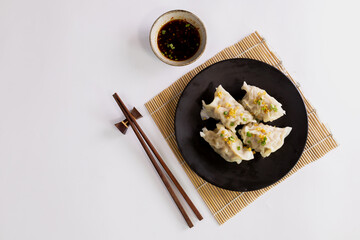 Chinese dim sum in a black plate and chopsticks