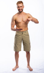 Fototapeta premium a muscular man in shorts holds his hand in front of him and points at it. place for an inscription. isolated, white background