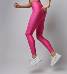 Closeup of sporty slim fitness woman in pink leggings and white sneakers does sport exercises,...