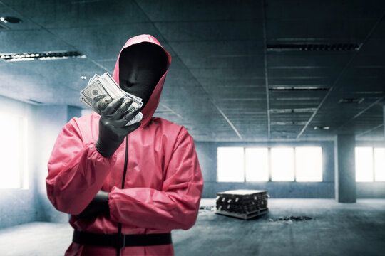 Criminal man in pink uniform and a hidden mask holding the money after the robbery