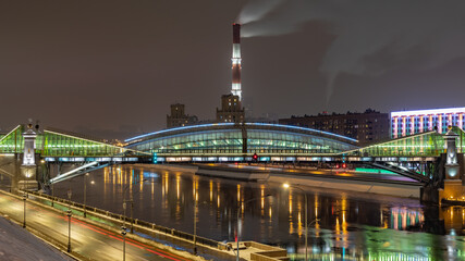 View of the colorful Bogdan Khmelnitsky bridge illuminated at night reflecting in the Moskova river. Moscow, Russia
