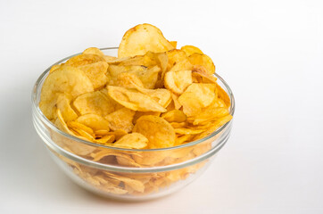Glass bowl with potato chips on a white background. Potato chips on a white background.