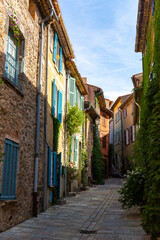 Fototapeta na wymiar Scenic view of medieval Provencal village of Grimaud with ancient stone buildings on narrow flowering cobbled streets on sunny fall day, France.
