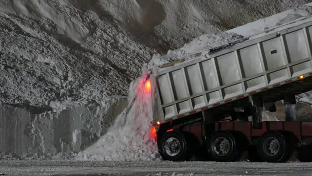 Dump truck unloading a pile of snow during the night after a winter storm