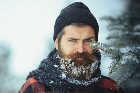 Christmas hipster. Winter portrait close up. Man with beard in winter forest with snow