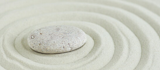 Fototapeta na wymiar Beige stone on sand with pattern lines, zen garden, meditation, harmony. Banner.Neutral colors.Poster