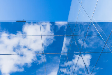 Blue sky in the clouds and its reflection on the glass surfaces of a modern building