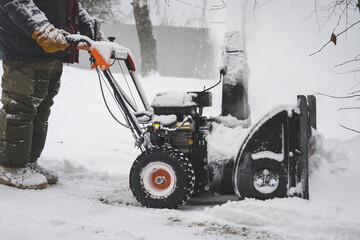 a man removes snow with a snow plow after a heavy snowfall near his house, close-up, blizzard, snow...
